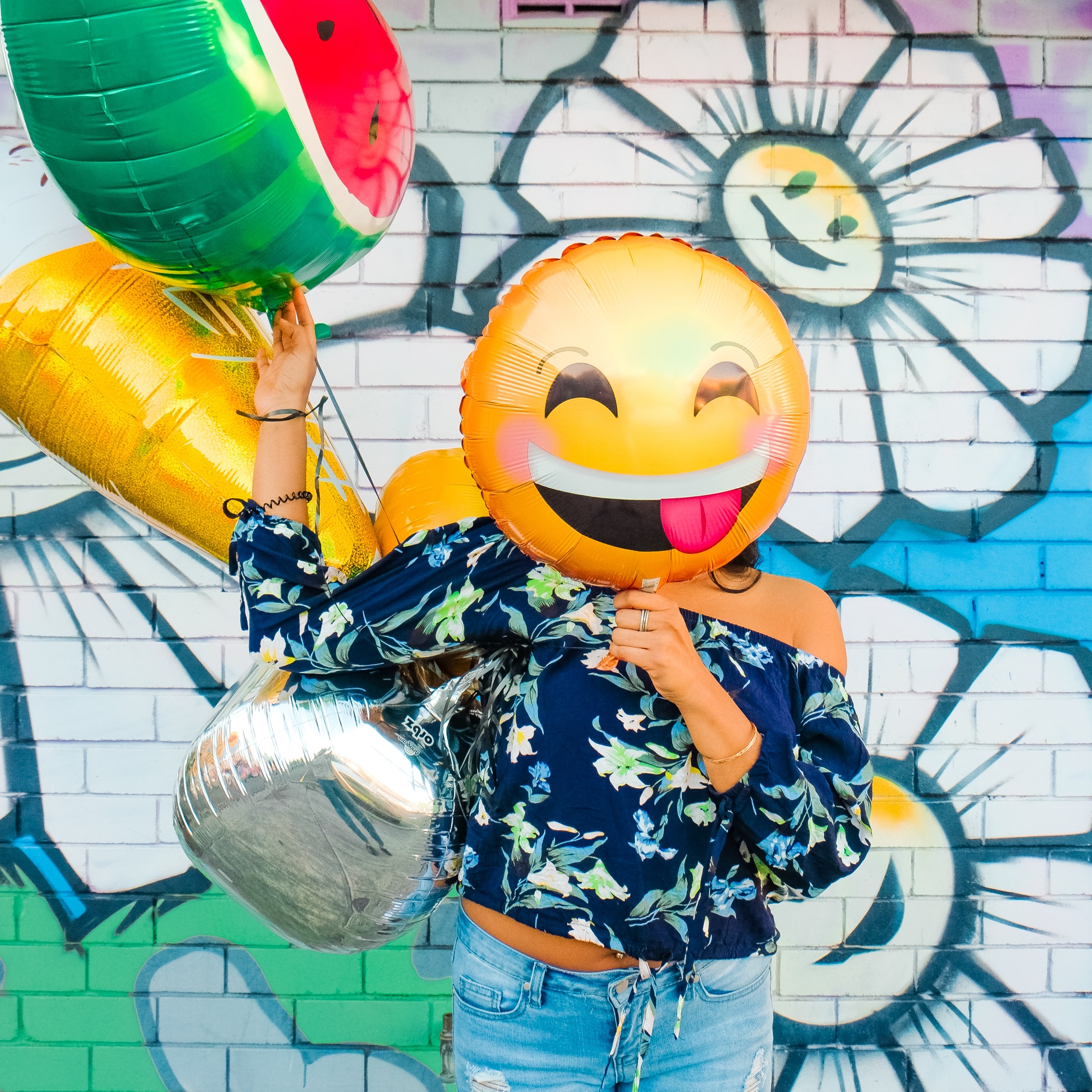 Woman holding a balloon with a happy face that covers her face.Image from Splash by Lidya Nada.