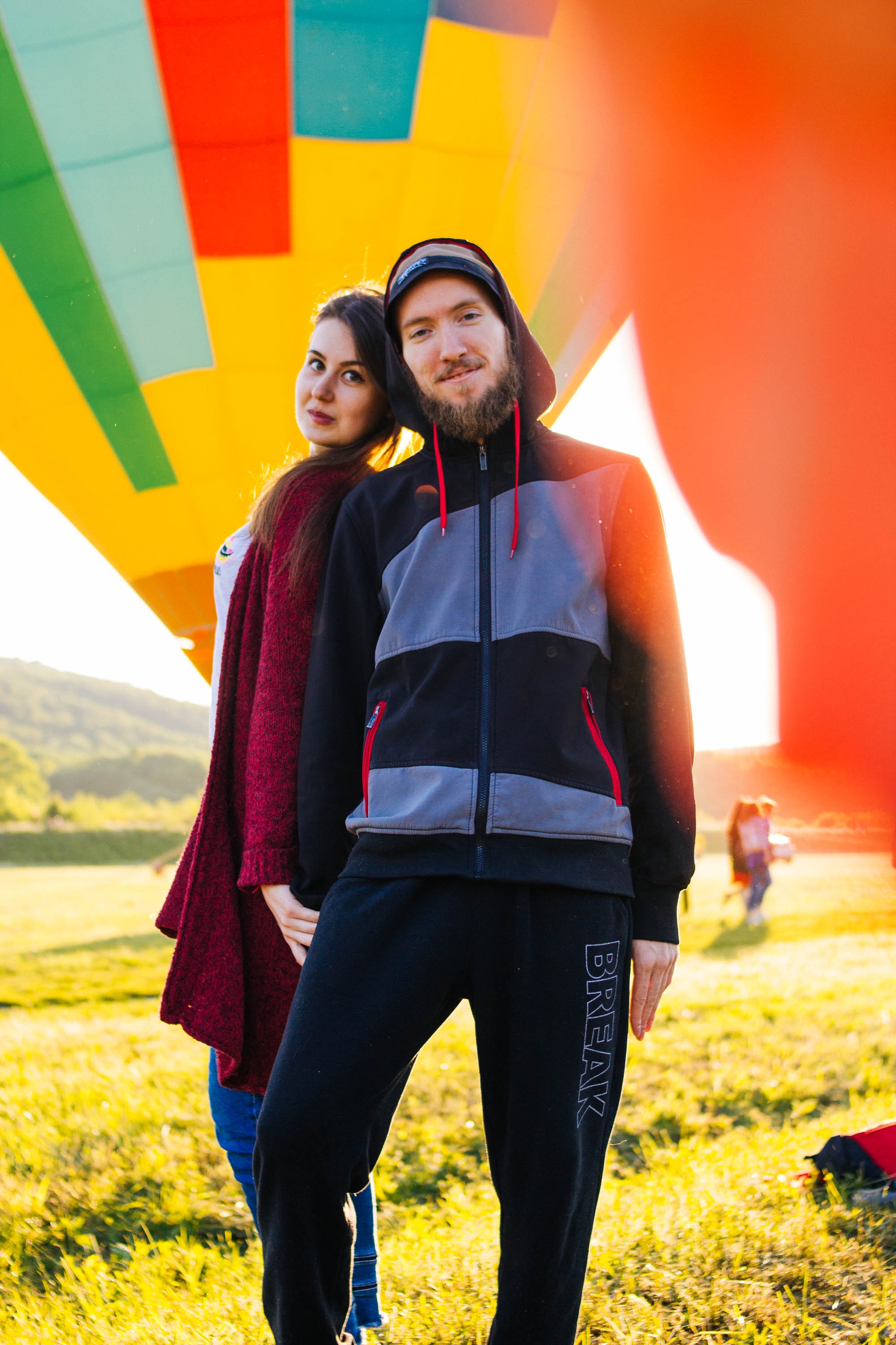 a couple having fun outside, in front of a rainbow hot air balloon. Image from unsplash by Olia Nayda